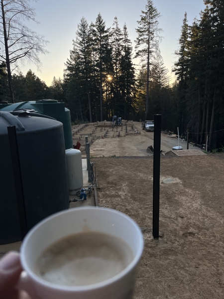 Sunrise over a building site, with a cup of coffee in the foreground